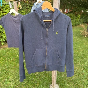 💙 Ralph Lauren mörkblå hoodie 🔥 Full-Zip L (passar S) - En tidlös hoodie som kombinerar klassisk design med bekväm passform. Mörkblå färg som är lätt att matcha, dragkedja framtill och den ikoniska broderade Polo-loggan på bröstet. Mjuk bomullsblandning, två framfickor och ribbade muddar vid ärmslut och nederkant. Passar perfekt för dig som gillar en mer figurnära look.  📏 Storlek på lappen: L – men passar bäst för dig som vanligtvis bär S 🧵 Material: Bomull (mjuk och skön) ✨ Skick: Mycket fint begagnat skick – inga fläckar eller hål  📦skickas snabbt