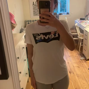 Vit Levi's t-shirt  - Vit t-shirt från Levi's i storlek s. Framsidan har ett stort svart tryck med Levi's-logga och blommiga detaljer. 