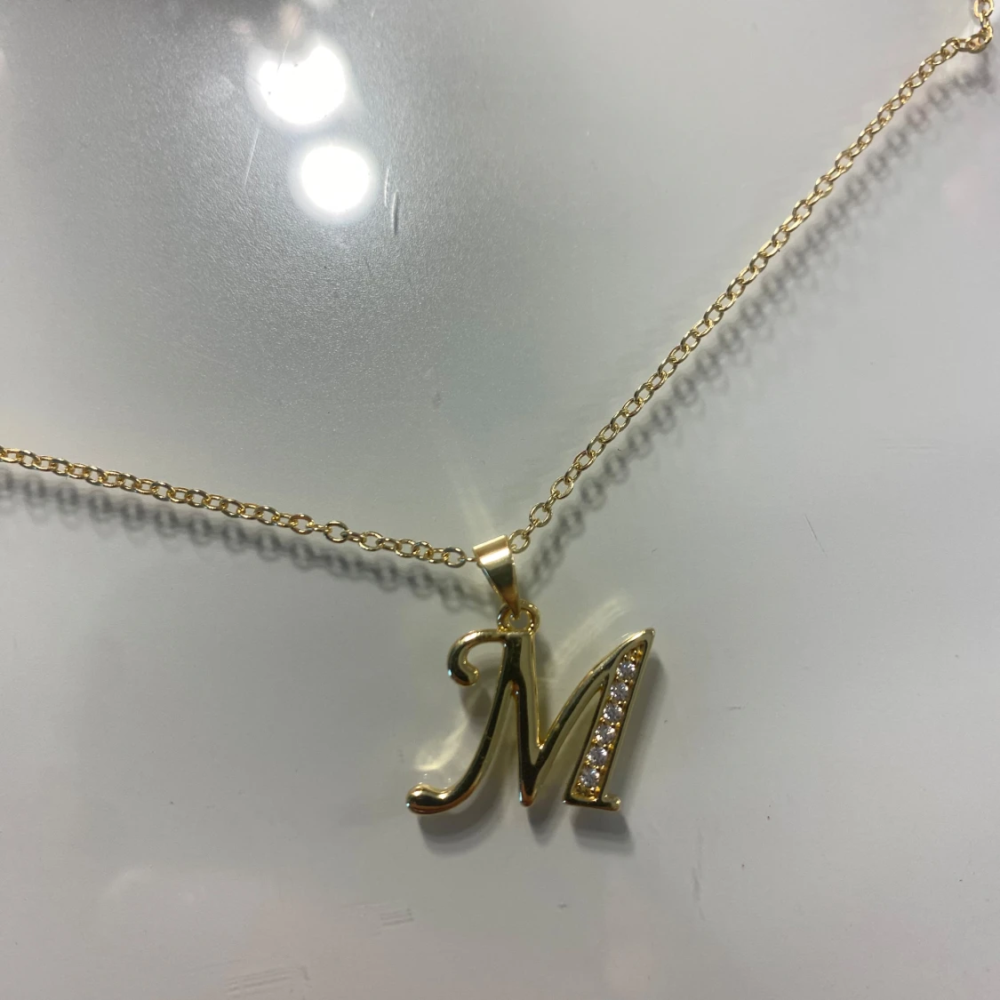 Guldigt halsband med M-berlock