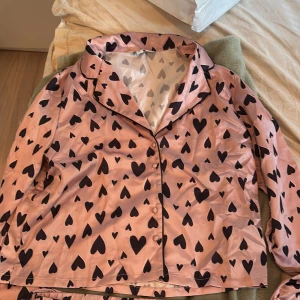 Rosa pyjamasshorts och skorta med hjärtan Miss Selfridge - Säljer ett super fint och supergulligt rosa pyjamassett från Miss Selfridge med svarta hjärtan över hela tyget. Perfekt för mysiga hemmakvällar!