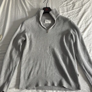 Grå ribbad half zip från Jack & Jones - Snygg grå ribbstickad tröja från Jack & Jones i storlek M. Passar perfekt nu när hösten och vintern kommer. Perfekt för lager-på-lager och mer avslappnad stil. Nypris 599kr mitt pris 149