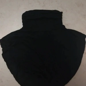 Svart och vit neckcovers - Två neckcovers i svart och vitt, båda med hög krage och mjukt, tunt bomullstyg. 