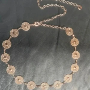Gyllene Concho Belt / Kedjebälte m Runda Medaljonger – Boho, Retro & Westernstil - Snyggt kedjebälte i guldfärgad metall med medaljonger i retrostil. Justerbar längd med hake och förlängningskedja, totalt ca 110 cm. Medaljongerna är ca 3 cm i diameter. En dekorativ accessoar som lyfter boho-, festival- och 70-talsinspirerade outfits. Snyggt över klänning, kjol eller utsvängda byxor.  Material: Metall Skick: Aldrig använt, i nyskick  Prutning accepteras ej, men jag erbjuder rabatt vid köp av flera saker. Kolla gärna mina andra annonser! 