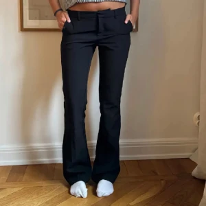 Lågmidjade kostymbyxor  - Snygga svarta kostymbyxor från Bik Bok med bootcut-silhuett och låg midja. Byxorna har bälteshällor, klassisk dragkedja och raka ben som släpper ut lite nertill. Perfekta till en trendig och clean look. 