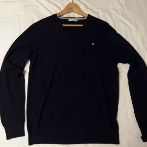 J.Lindeberg V-ringad tröja i bomull - Klassisk v-ringad tröja från J.Lindeberg i bomull. Finns i både svart, brun och röd med diskret logga på bröstet. Långärmad modell med ribbade muddar och stilren passform som funkar till allt. Perfekt för dig som gillar enkel och snygg stil. Vill du köpa en tröja separat så kostar just en tröja 200 kr styck men du kan få alla tre för 500 vid en snabb affär! 