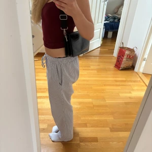 Svart axelväska från Gina Tricot - Säljer en svart axelväska från Gina Tricot med croco-mönstrad yta och bred justerbar axelrem. Väskan har ett stilrent och modernt utseende, perfekt för att lyfta din outfit. Tillverkad i syntetmaterial och har dragkedja på insidan.