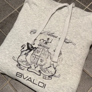 Ljusgrå hoodie från BVALDI med tryck - Riktigt snygg och eftertraktad hoodie från Bvaldi, säljer då den sitter lite tajt så den är använd nån gång!🙌 Nypris 899! Jag är 175, den passar om du är ca 170-175. Skick 10/10!!✅ Hör gärna av dig vid frågor eller funderingar, priset kan diskuteras vid snabb affär!