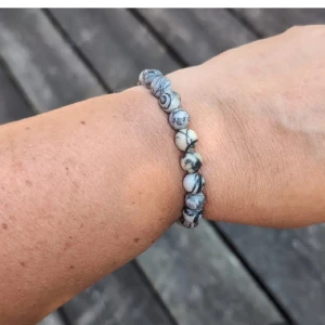 Elastiskt armband med marmorerade pärlor - Snyggt armband med runda pärlor i vit, grå och beige med marmorerat mönster. Pärlorna är trädda på elastisk tråd så det är lätt att ta på och av. Perfekt accessoar för en chill och stilren look. nytt