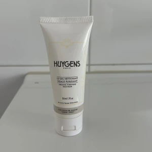 Huygens ansiktsrengöring 50ml - En vit tub med Huygens Paris Le Gel Nettoyant Visage Purifiant, en ekologisk ansiktsrengöring på 50 ml. Innehåller naturliga ingredienser och är parfymfri. Perfekt för att rengöra huden och balansera talgproduktionen. Smidig att ta med i väskan.