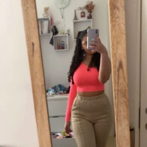 Neonrosa one shoulder topp Forever 21/hm.  Neon rosa tub topp med en långärmad ärm - Säljer en neonrosa croppad topp från Forever 21 eller från HM (glömt vart jag köpt ifrån) med one shoulder-design och lång ärm på ena sidan. Toppens material är stretchigt och mjukt, perfekt för dig som vill sticka ut. Snygg passform som framhäver midjan och perfekt färg nu till sommaren!