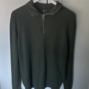 Olivgrön stickad tröja H&M half zip - Säljer en olivgrön stickad tröja från H&M med zip-dragkedja vid kragen. Perfekt för lager-på-lager och chill stil. Tröjan är töjbar och har relaxed fit