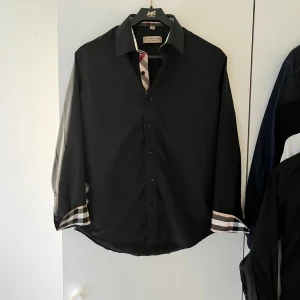 Burberry skjorta - Hej! Säljer nu denna otroligt feta burberry skjorta i toppen skick, 10/10, broderad logga på bröstet med det klassiska burberry mönstret vid armarn och längst knapparna, storlek M passar 180-185 cm skulle ja säga, bara att höra av sig vid funderingar och pris kan diskuteras 