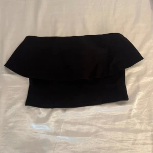 Svart bandeau tubtopp  - svart bandeau tubtopp med volang upptill. Aldrig använt💕så nyskick , passar mig som bär S och xs även