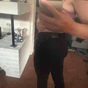 Svarta bootcut jeans från Gina tricot  - Säljer ett par svarta jeans med bootcut-modell och midwaist. Sitter tajt över låren och släpper ut vid vaden för en snygg siluett. Klassisk femficksdesign och knappgylf. Perfekta till sneakers eller boots.