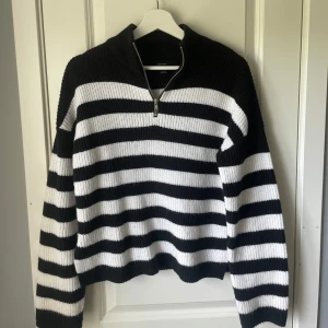 Svartvit randig stickad tröja  - Säljer en stickad tröja med breda svarta och vita ränder. Tröjan har halv dragkedja framtill och liten slits i sidan🤩