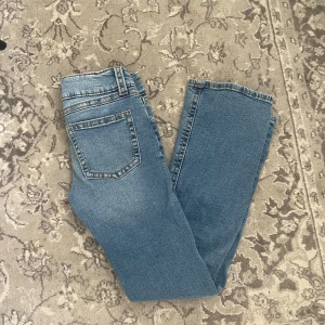Blå jeans med dubbla knappar - Säljer ett par klassiska blå jeans med dubbla knappar i midjan . Jeansen är mid/low waist och lite åt bootcut hållet