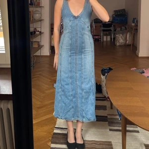Jeansklänning, långklänning i denim, Zara - Helt ny jeansklänning. Klänningen har en figurnära passform upptill och faller rakt ner till. Smickrande passform med deagkedja i sidan. Helt ny med prislappen kvar, nypris 499. Slutsåld då den är från 2023