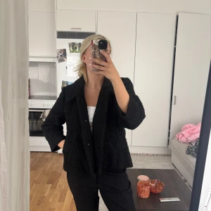 Svart bouclejacka från Vila - Säljer en svart bouclejacka från Vila med stor krage och två framfickor. Jackan har en lite boxig passform och är helfodrad. Perfekt för höst och vår, enkel att styla till olika outfits.