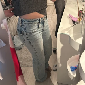 Ljusblå raka jeans - Säljer ett par ljusblå jeans med rak passform och klassiska fem fickor. Jeansen har normalhög midja och stängs med dragkedja och knapp. Perfekta till vardags för en avslappnad stil.