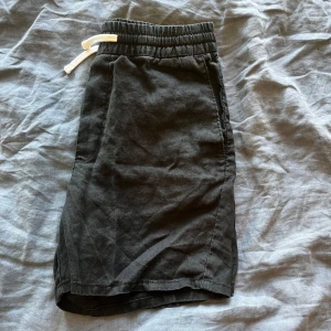 Svarta linne shorts från Weekday 100% linne - Svarta shorts från Weekday med elastisk midja och vit snörning. Klassisk passform med sidofickor och en bakficka. Tillverkade i 100% linne förutom fickorna som är i bomull