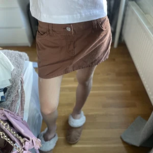 Brun kort jeanskjol  - Säljer en brun kort jeanskjol med speciella fickor där bak och knappstängning fram. den har lappen kvar, Säljer då den inte kommer till användning!😊