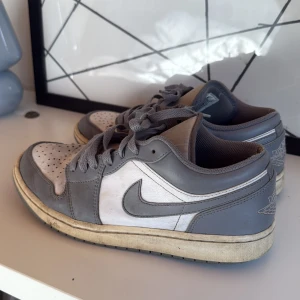 Nike Air Jordan 1 Low i grått och vitt - Säljer ett par Nike Air Jordan 1 Low i grått och vitt. Säljs pga för små, de är lite smutsiga men går bort om man tvättar. Inte använt på 3 år