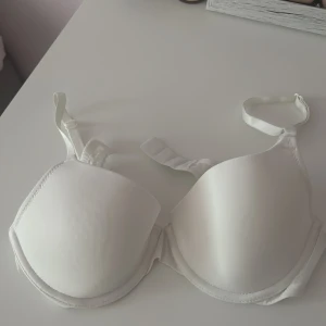 Vit bh från H&M - Säljer en klassisk vit bh från H&M med vadderade kupor och justerbara axelband. Bh:n har en slät design och är tillverkad i mjukt material för extra komfort. Perfekt basplagg i garderoben.