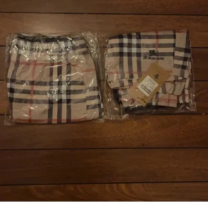 Beige rutiga shorts från Burberry - Snygga beige shorts från Burberry med klassiskt rutigt mönster i svart, vitt och rött. Shortsen har elastisk midja och sidofickor. Perfekta för en trendig och avslappnad stil.