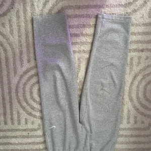 Grå mjukisbyxor från Nike - Säljer ett par klassiska grå mjukisbyxor från Nike med resår i midjan och en bakficka. Perfekta för en avslappnad stil och riktigt sköna att ha på sig dom är inte samma storlek som det står de passar mig  när jag har storlek S och M
