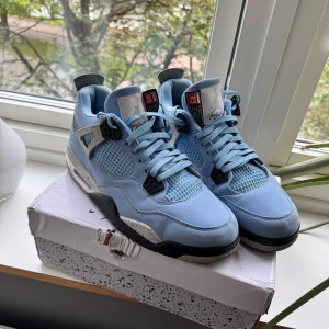 Nike Air Jordan 4 University Blue - Säljer ett par Nike Air Jordan 4 University Blue. Skorna är ljusblå med vita och svarta detaljer, meshpaneler och klassisk Jumpman-logga på hälen. STORLEK 45, MEN PASSAR OCKSÅ 44!