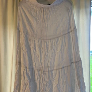 Vit lång kjol från lager 157 - Luftig vit kjol från lager 157 med smockad resår upptill. Kjolen har en lös passform och faller fint i flera lager. Perfekt för varma dagar eller sommarens tillfällen.