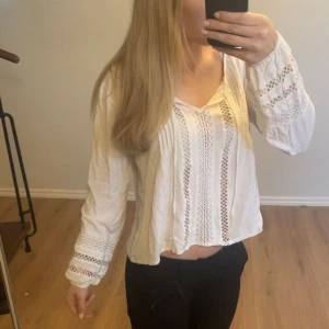 Vit blus med spetsdetaljer - Säljer en söt vit blus med långa ärmar och fina spetsdetaljer framtill och vid ärmsluten. Materialet känns luftigt och bekvämt. Säljer för att den inte kommer till användning, inga defekter förutom att lappen är borta💗