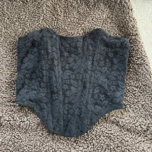 Svart spetskorsett - Säljer en svart korsett med vacker spetsdetalj och mönster. Använd nån enstaka gång bara 