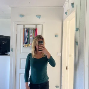 Mörkgrön långärmad topp - Säljer en mörkgrön långärmad topp med rund halsringning. Skön och stretchig i materialet.