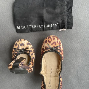 Leopardmönstrade ballerinaskor Butterfly Twists - Använd sen gång!Säljer ett par ballerinaskor från Butterfly Twists med leopardmönster och svarta rosetter framtill. Skorna är vikbara och kommer med en svart påse för enkel förvaring.