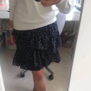 Minikjol - Säljer en superfin blommig minikjol från Stradivarius i storlek XS. Kan inte tyda vad det är för färg egentligen men antingen svart eller marinblå😅 Kjolen har volanger, samt en elastisk midja🖤