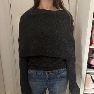 Mörkgrå stickad tröja - Mysig mörkgrå stickad tröja med lång ärm och avslappnad passform. Tröjan har en enkel design utan synliga detaljer och är perfekt för kyligare dagar.