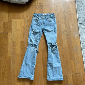 Ljusblå bootcut jeans med slitningar - Säljer mina bootcut jeans som är väldigt lågmidjade då dom är för små för mig. Har gjort hålen själv. Perfekta nu för sommaren ☺️