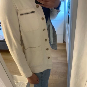 Beige jeansjacka från Vero Moda - Säljer en beige jeansjacka från Vero Moda med knappar framtill, bröstficka med dragkedja och två stora fickor. Jackan har lång ärm och rak passform.