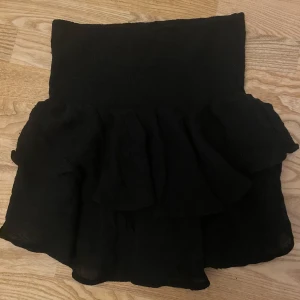 Svart volangkjol - Säljer en jättefin svart kortkjol som passar perfekt till olika outfits.