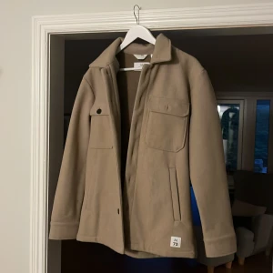 Beige overshirt från Matinique  - Säljer en stilren beige overshirt från Weekday med klassisk krage och två stora bröstfickor. Jackan har knäppning framtill och vid ärmslut, perfekt för lager-på-lager under hösten eller våren. Köpt för 1500kr, hör av dig vid minsta fundering🙌Pris går att sänka vid snabb affär