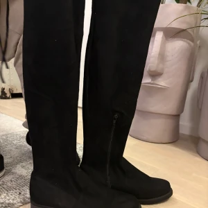 Svarta höga stövlar - Snygga svarta höga stövlar med låg klack och grov sula. Gjorda i mocka-liknande material med dragkedja på insidan för enkel påtagning. Perfekta till hösten