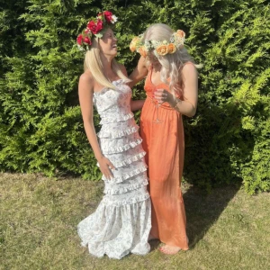 Vit långklänning med volanger och blommor - Superfin vit långklänning med blommigt mönster och flera lager volanger. Klänningen är axelbandslös och har en romantisk vibe, perfekt för sommarens alla tillfällen. Lätt och luftig känsla med snygg passform.