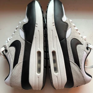 Nike Air Max 90  - Nike Air Max 90 i färgerna svart/vit/beige. Ovandel i mesh och mocka med svarta läderdetaljer och vit snörning. Ikonisk Swoosh-logga på sidan och bekväm platt sula.    Endast testade.  Storlek 40,5