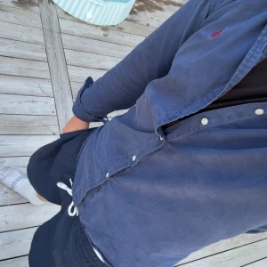 Blå skjorta från Ralph Lauren M - Säljer en klassisk blå skjorta från Ralph Lauren i storlek M. Skjortan har långa ärmar, vita knappar och den ikoniska röda loggan broderad på bröstet. Tillverkad i mjuk bomull och passar perfekt till jeans eller shorts.