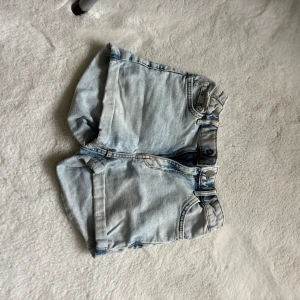 Ljusblå jeansshorts med uppvik - Snygga ljusblå jeansshorts med klassisk femficksdesign och uppvikta benslut. Shortsen har bälteshällor, knapp och dragkedja framtill. Perfekta för varma dagar och en avslappnad stil.