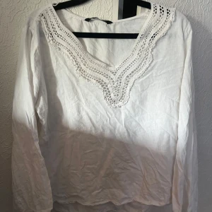 ZARA Vit blus med spetsdetaljer  - Säljer en vit blus med lång ärm och snygg v-ringning med spetsdetaljer runt halsen. Jätte gullig till sommaren och våren 🥹