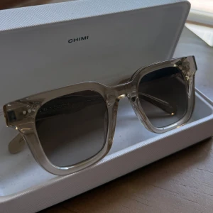 Chimi 04 - Snygga solglasögon från Chimi i modellen 04 Ecru. De har en transparent beige ram i fyrkantig form och mörka tonade glas. Ramen är tillverkad i acetat och ger en clean och modern vibe. Perfekta för att lyfta din stil i sommar.
