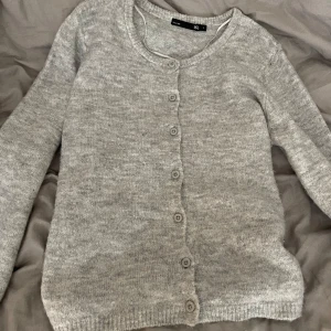 Grå kofta från 157, storlek S - Mysig grå kofta från 157 i storlek S. Den är stickad och har rund halsringning samt knappar hela vägen framtill. Använd 2 gånger!!