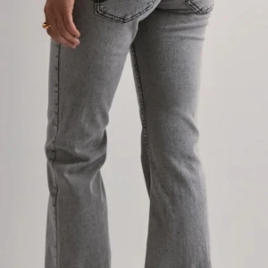 Grå bootcut jeans med broderade fickor - Snygga grå jeans med bootcut passform och coola broderade detaljer på bakfickorna. Jeansen har klassisk femficksdesign och markerade sömmar. Perfekta för dig som vill ha en trendig och avslappnad look.